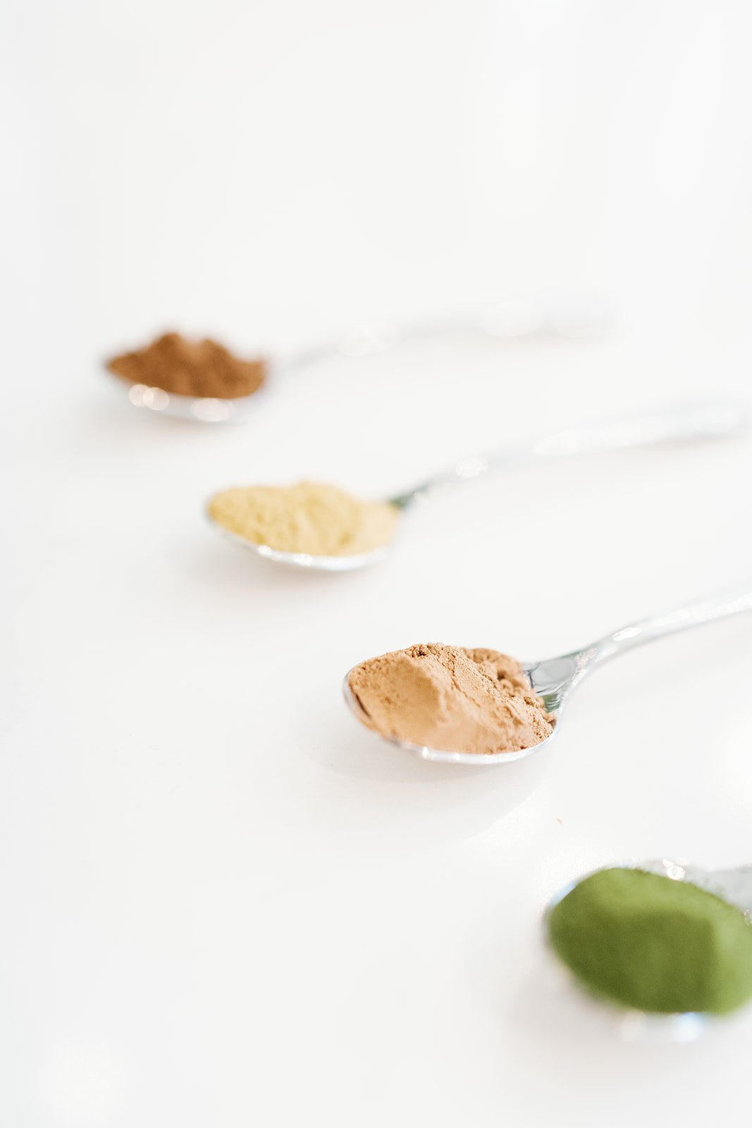 4 spoons laid out with green tea extract powder, turmeric powder, cinnamon powder and chia powder